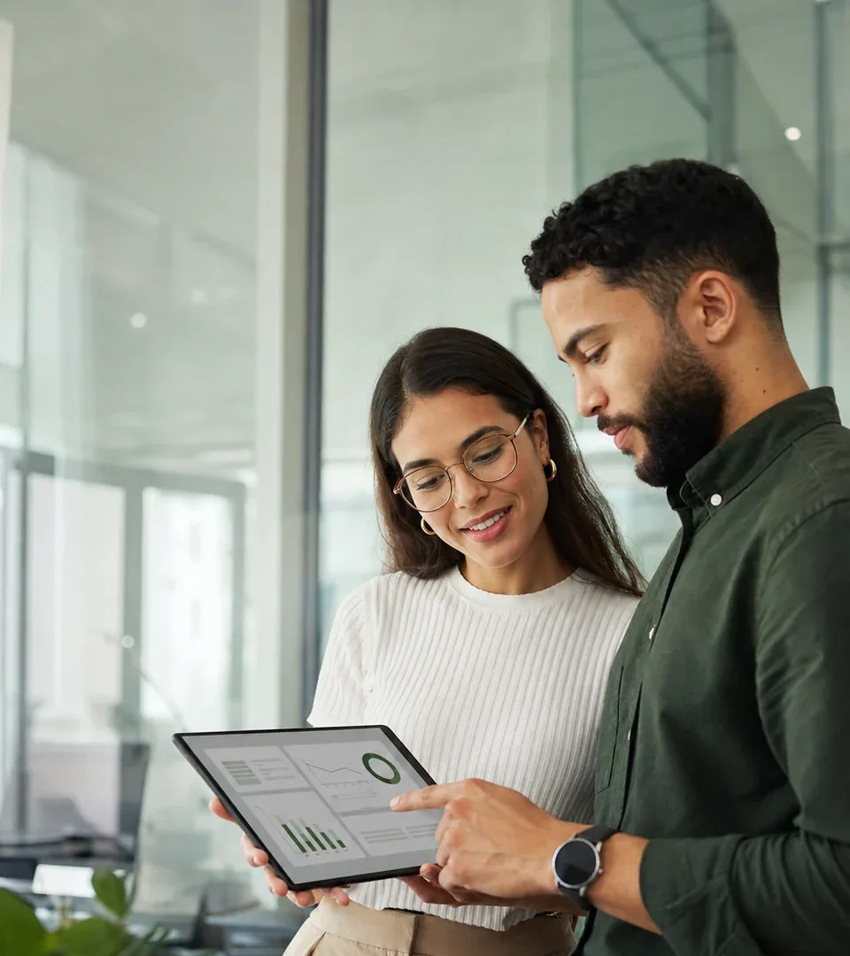 Equipe analisando um painel de gestão financeira em tablet dentro de um escritório moderno.